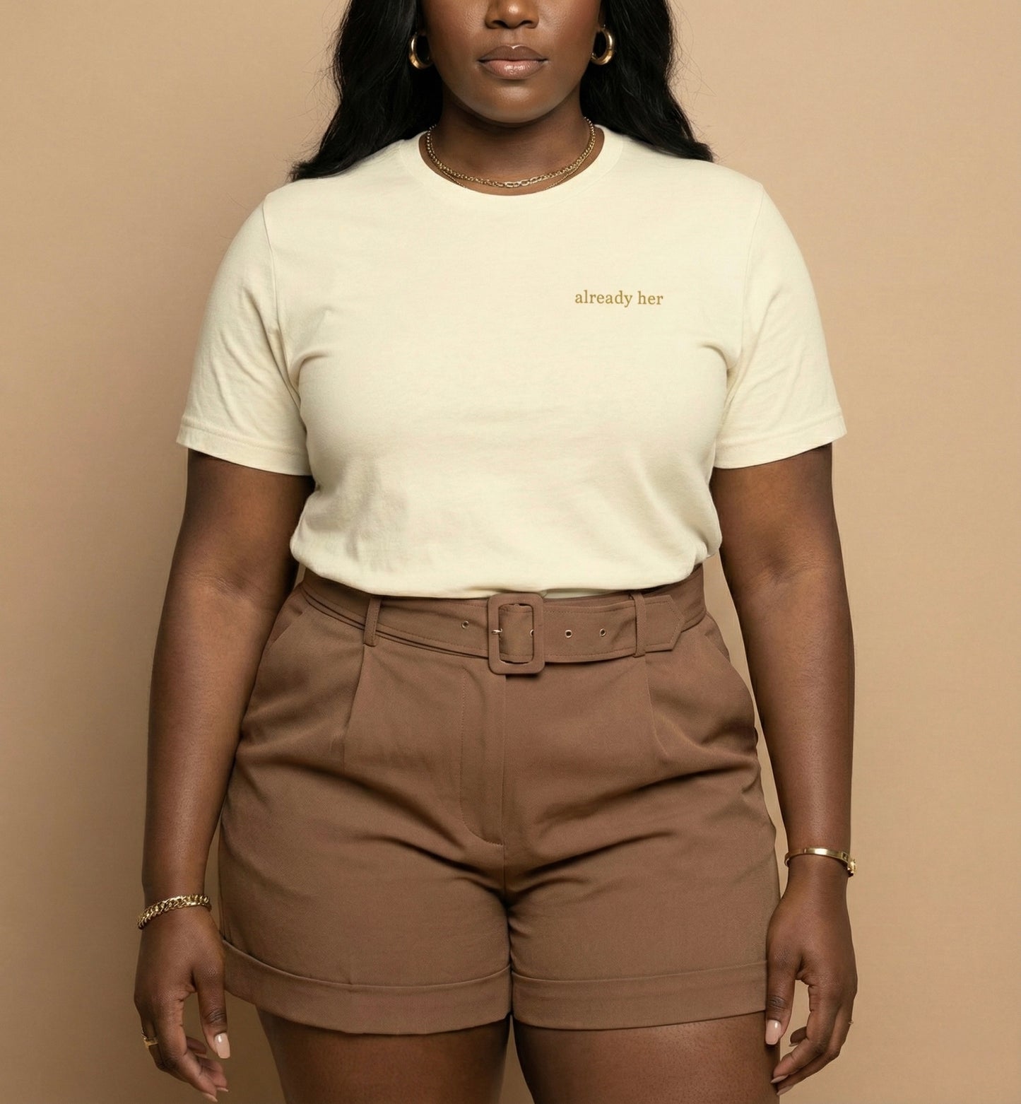 Person wearing a white t-shirt with text and brown shorts against a beige background