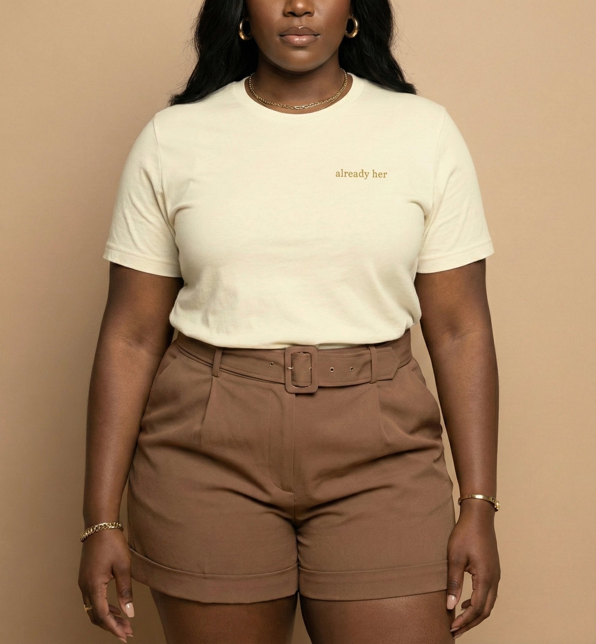 Person wearing a white t-shirt with text and brown shorts against a beige background